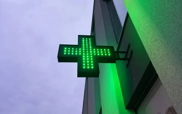 Croix verte lumineuse sur la façade d’une pharmacie, illustrant les prestations de nettoyage de SRIM à Bagnoles-de-l’Orne.